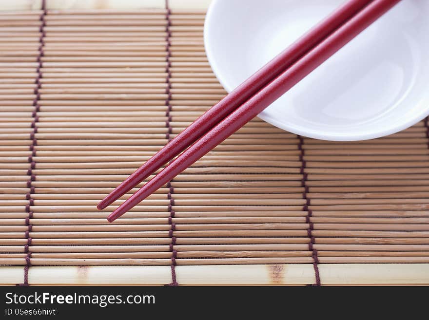 Two chopsticks next to a red and white bowl