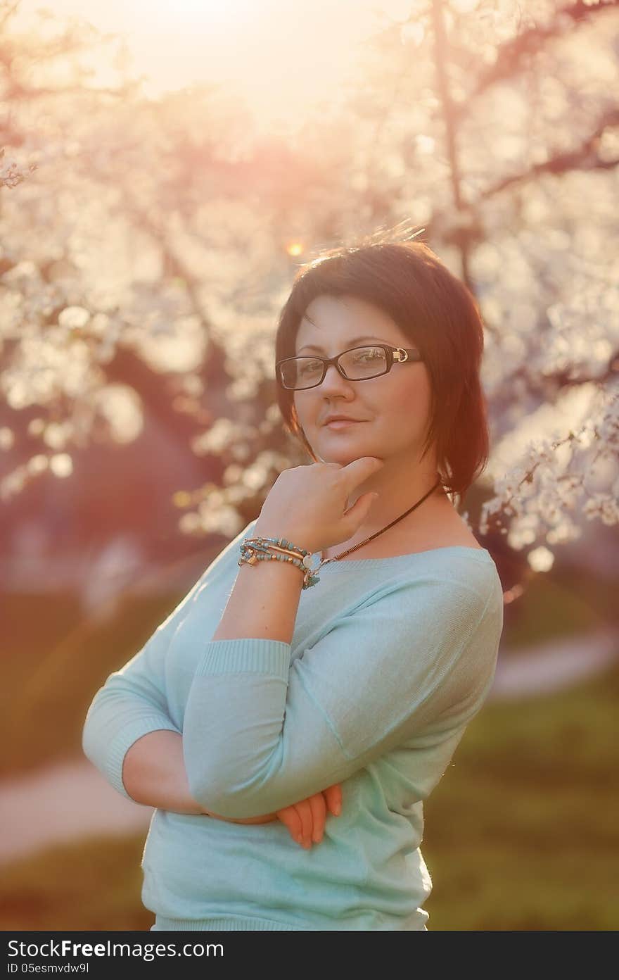 Portrait of a girl with glasses on the background of a flowering tree in spring in the garden