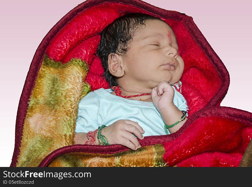 New born baby sleeping on red blanket and isolated on light pink background