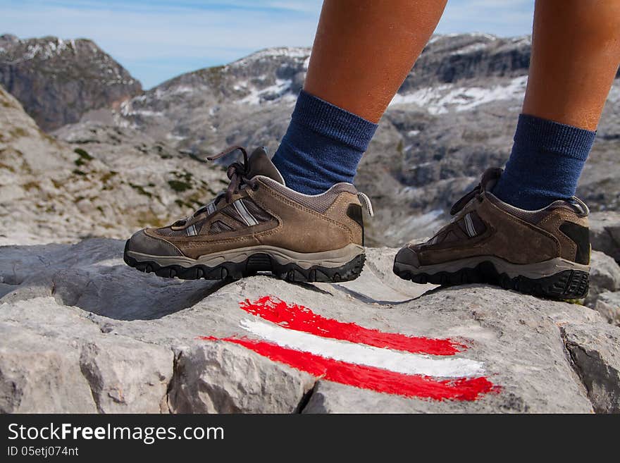 Feet of hiking woman in mountains and marked path. Feet of hiking woman in mountains and marked path