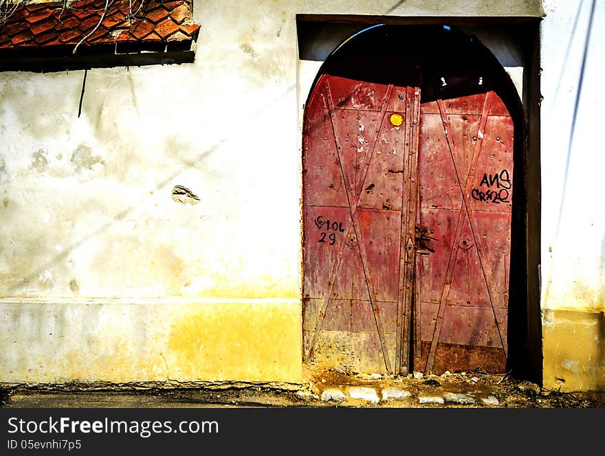 Red, decayed, iron door on a white wall