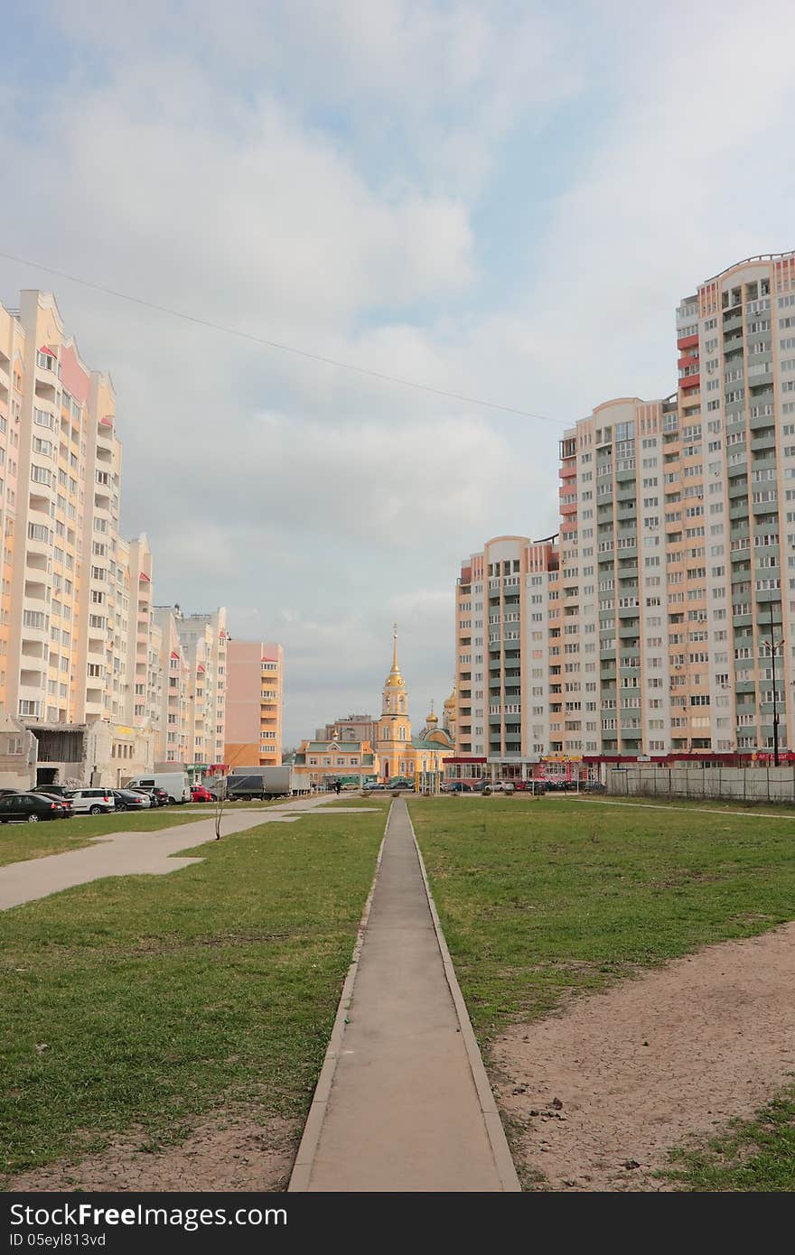 The narrow walkway to the temple, surrounded by modern multi-storey buildings in a residential area of the city. The narrow walkway to the temple, surrounded by modern multi-storey buildings in a residential area of the city.