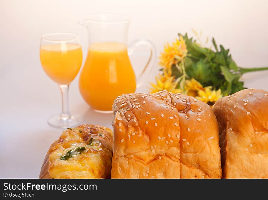 Some breads, bottles of juice with flowers on table. Some breads, bottles of juice with flowers on table