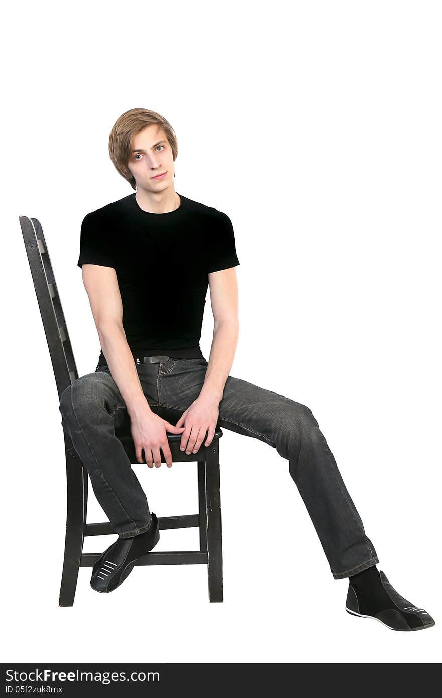 Handsome young man in black clothes sitting on a chair on white background. Handsome young man in black clothes sitting on a chair on white background