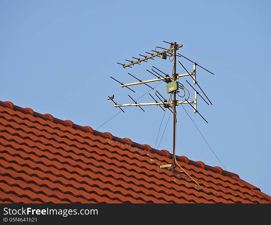 Receiver antenna on red roof in sunlight. Receiver antenna on red roof in sunlight