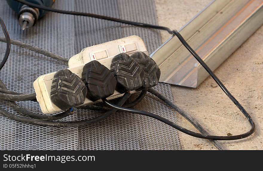 Electrical multi-extender plug being used on construction site with power tool in background. Electrical multi-extender plug being used on construction site with power tool in background