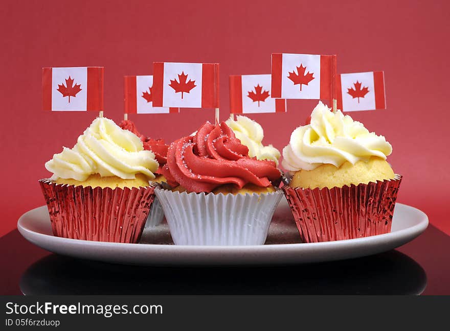 Red and White cupcakes with Canadian maple leaf national flags against a red background for Canada Day or Canadian national holidays.