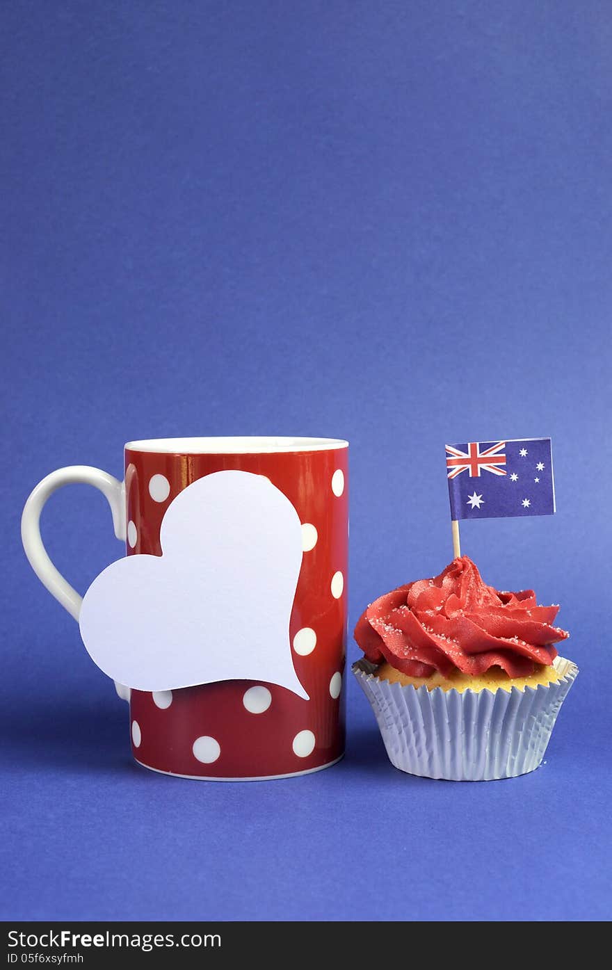 Australian theme red, white and blue cupcake with national flag and red polka dot coffee mug and white heart tag for your text here, for Australia Day, Anzac Day or national holiday against a blue background. vertical with copy space for your text here. Australian theme red, white and blue cupcake with national flag and red polka dot coffee mug and white heart tag for your text here, for Australia Day, Anzac Day or national holiday against a blue background. vertical with copy space for your text here.