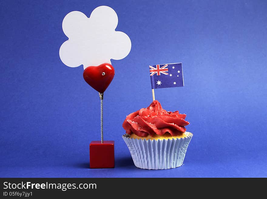 Australian theme red, white and blue cupcake with national flag, and sign for your text here, for Australia Day, Anzac Day or national holiday against a blue background. Australian theme red, white and blue cupcake with national flag, and sign for your text here, for Australia Day, Anzac Day or national holiday against a blue background.