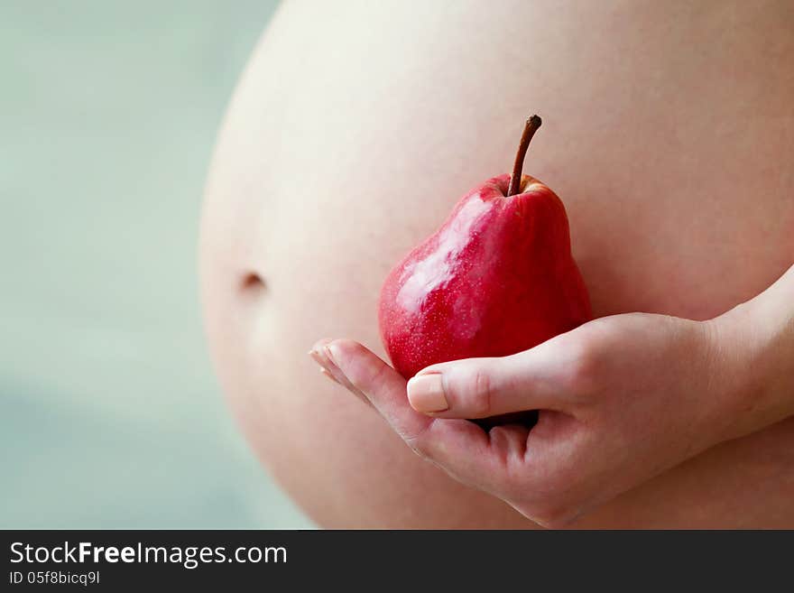 Pregnant woman belly and red pear