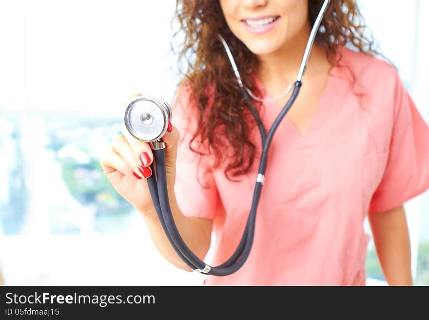 Close-up of a happy friendly beautiful nurse holding stethescope about to check a heartbeat. Close-up of a happy friendly beautiful nurse holding stethescope about to check a heartbeat