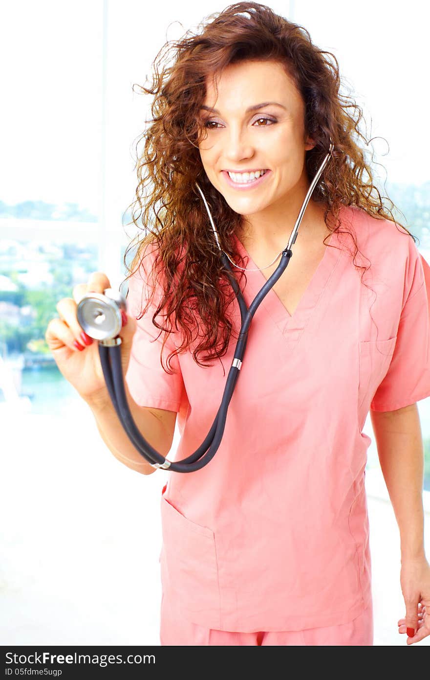 Close-up of a happy friendly beautiful nurse holding stethescope about to check a heartbeat. Close-up of a happy friendly beautiful nurse holding stethescope about to check a heartbeat