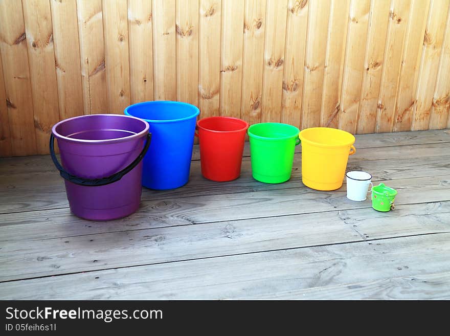 Set from seven colourful buckets on a wooden background. Set from seven colourful buckets on a wooden background