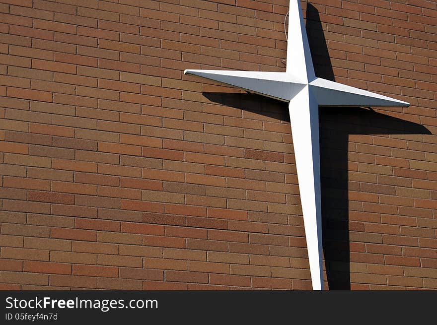 White Cross on outdoor Red Brick Wall building siding. White Cross on outdoor Red Brick Wall building siding