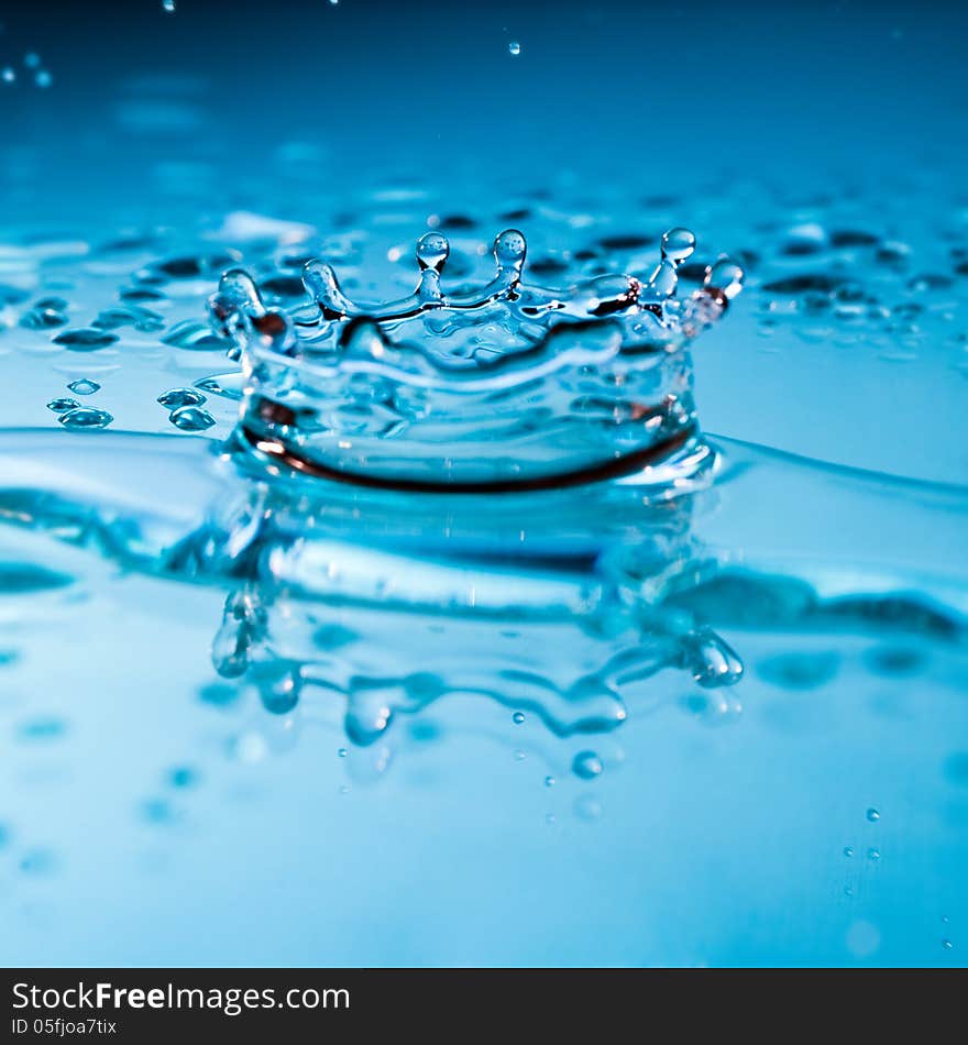 Water splash with suspended droplets in clean fresh pure blue water with a reflection