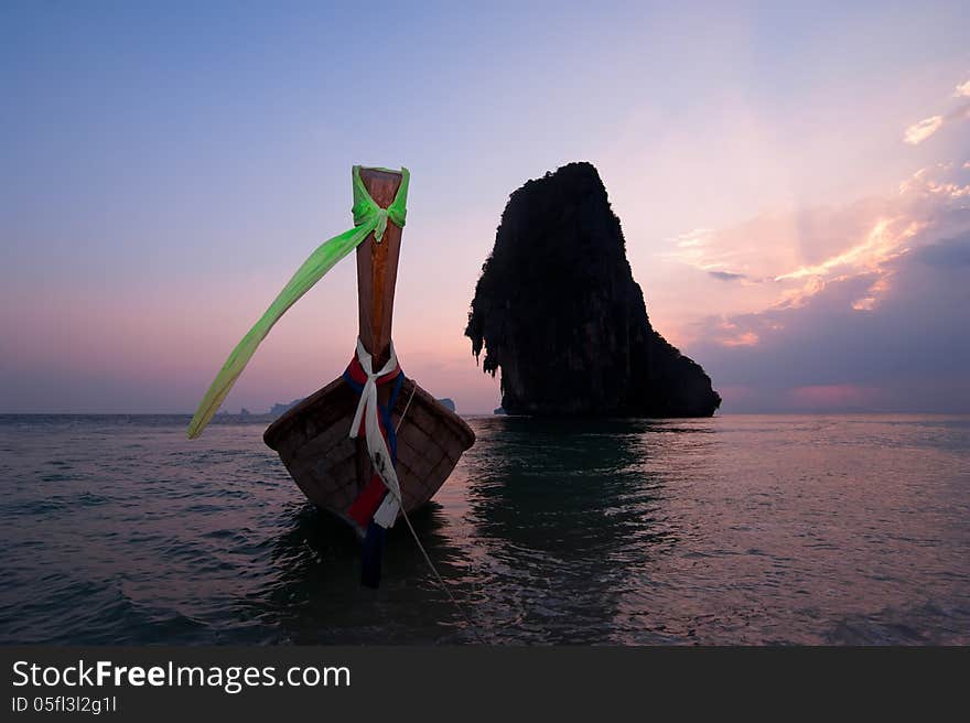 Sunset at tropical beach landscape. Thai traditional long tail boat at the ocean coast with rock formation island under evening sun. Pranang cave beach, Railay, Krabi, Thailand. Sunset at tropical beach landscape. Thai traditional long tail boat at the ocean coast with rock formation island under evening sun. Pranang cave beach, Railay, Krabi, Thailand