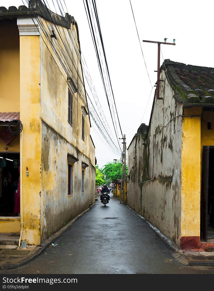 Man driving motorcycle on small alley in Hoi an, Vietnam. Man driving motorcycle on small alley in Hoi an, Vietnam