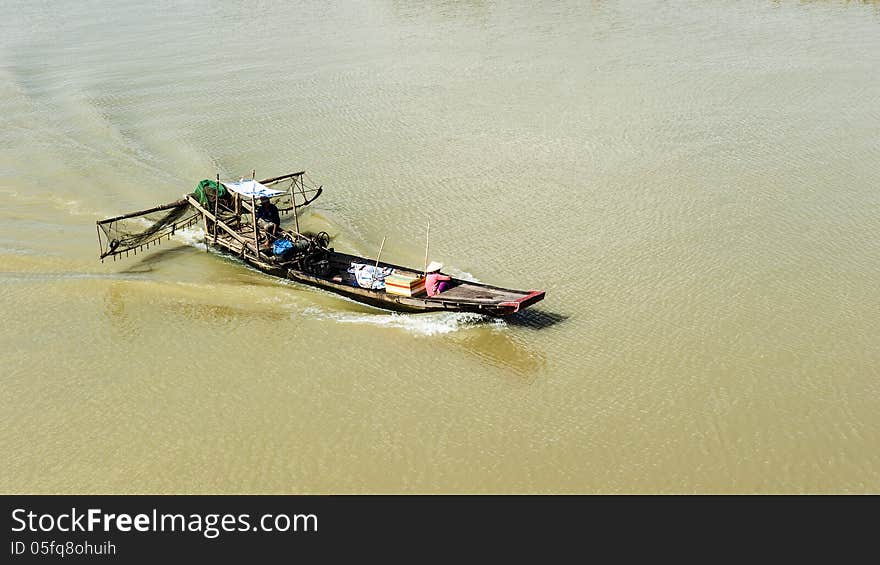 Fishing boat on the river with woman wearing conical hat