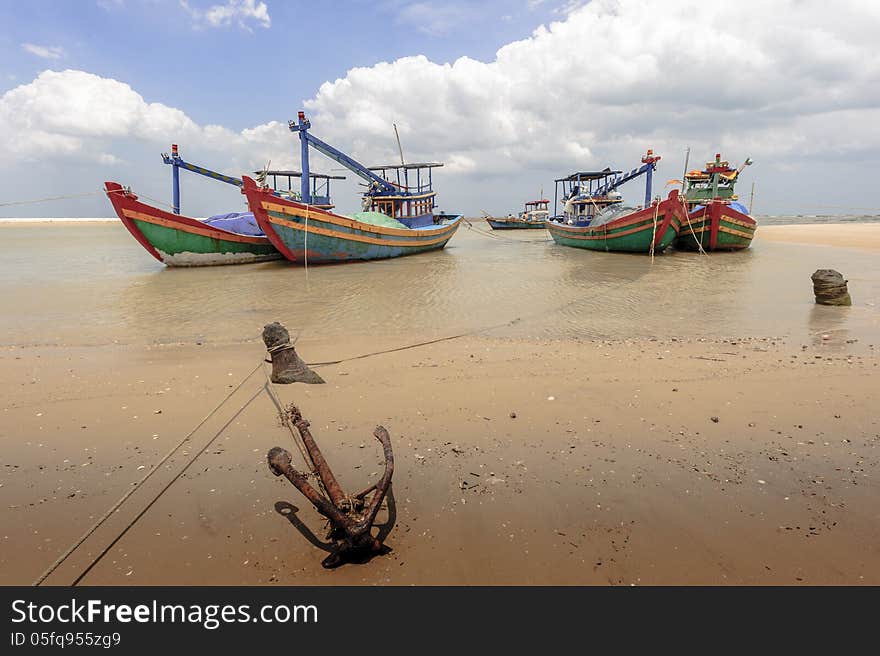 The fishing boats and the anchor at the seaside with cloudy sky at background. The fishing boats and the anchor at the seaside with cloudy sky at background