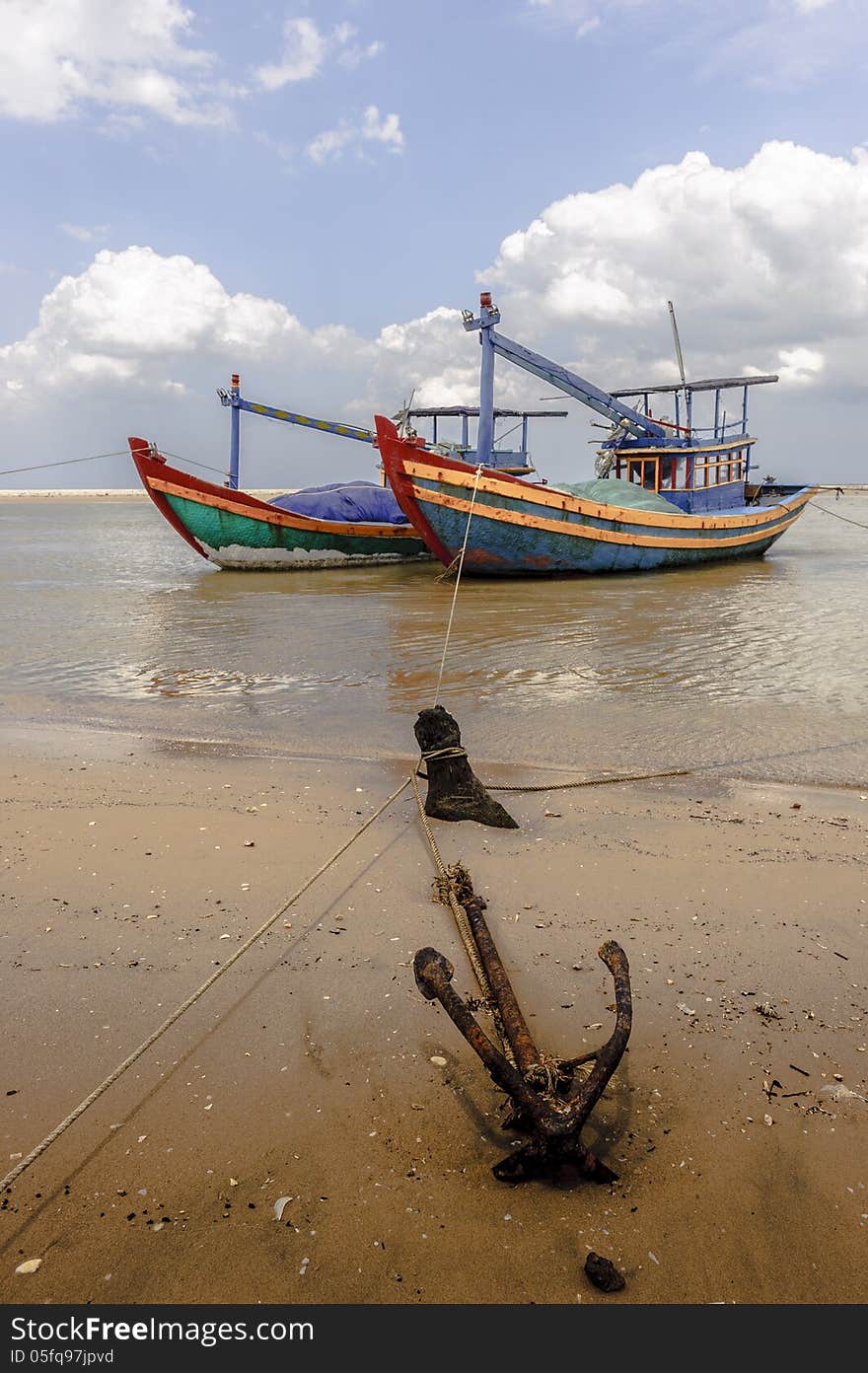 The fishing boats and the anchor at the seaside with cloudy sky at background. The fishing boats and the anchor at the seaside with cloudy sky at background