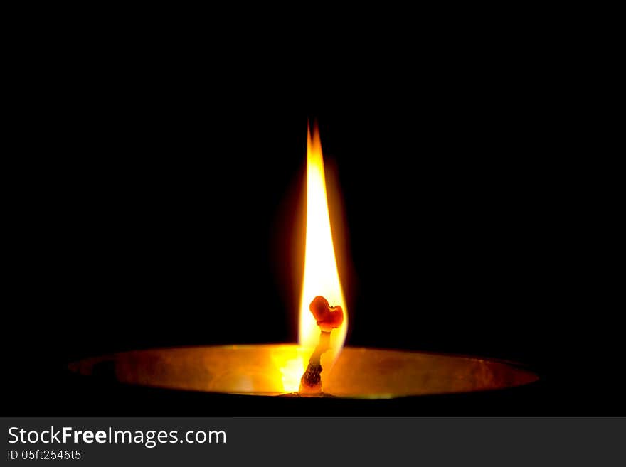 Flame of a Diya isolated on dark black background.