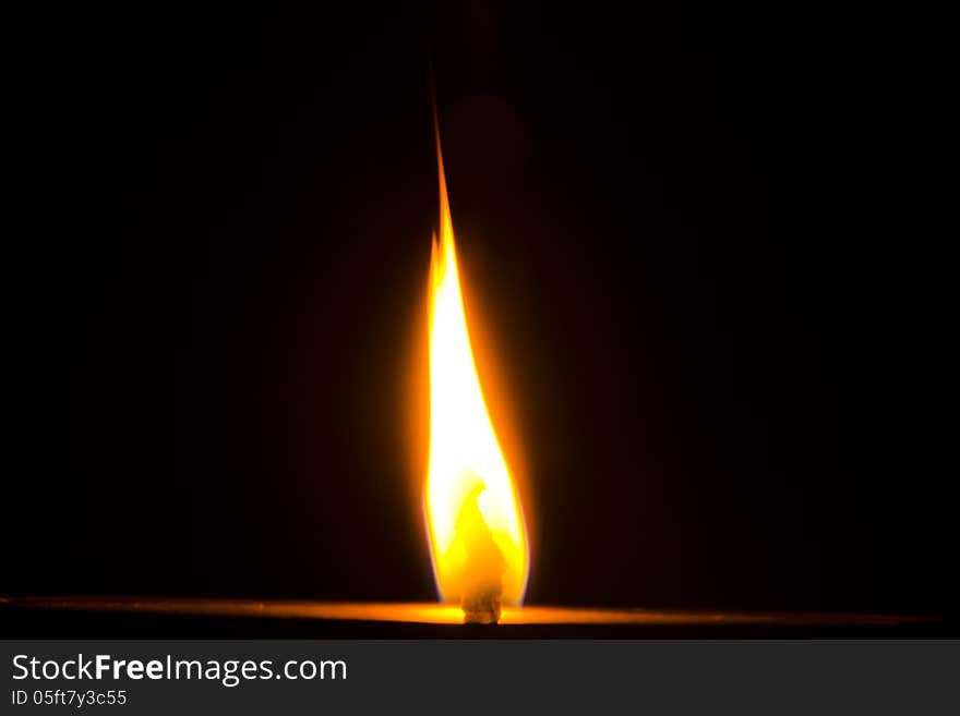 Flame of a Diya on dark black background.