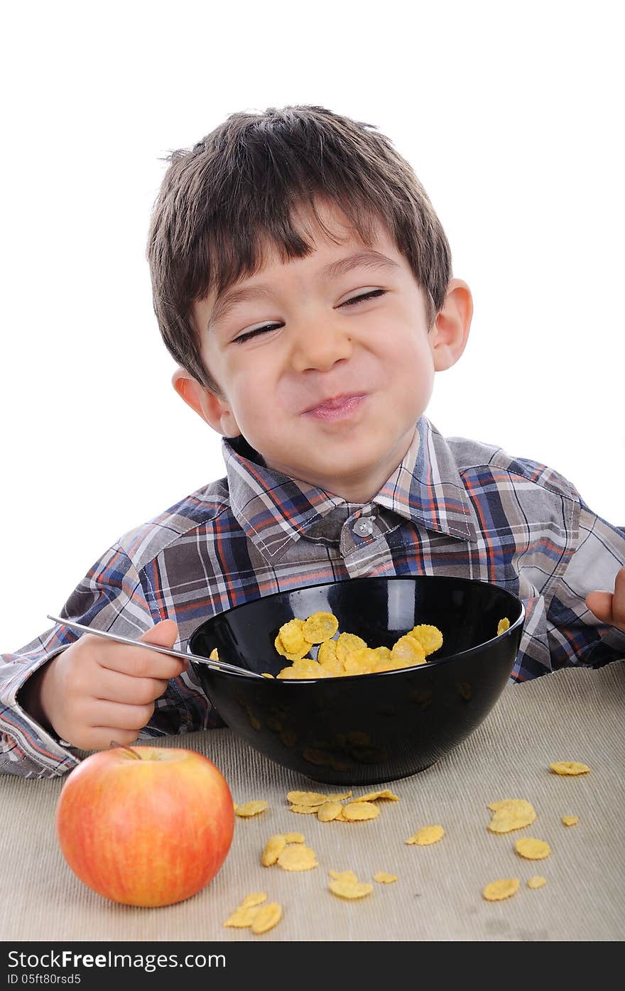 White cute boy is eating corn flakes for breakfast.