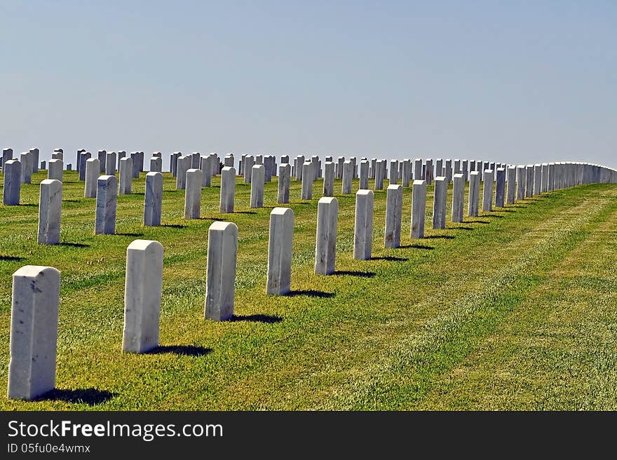 Gravestones of a large cemetary on a grassy hillside.