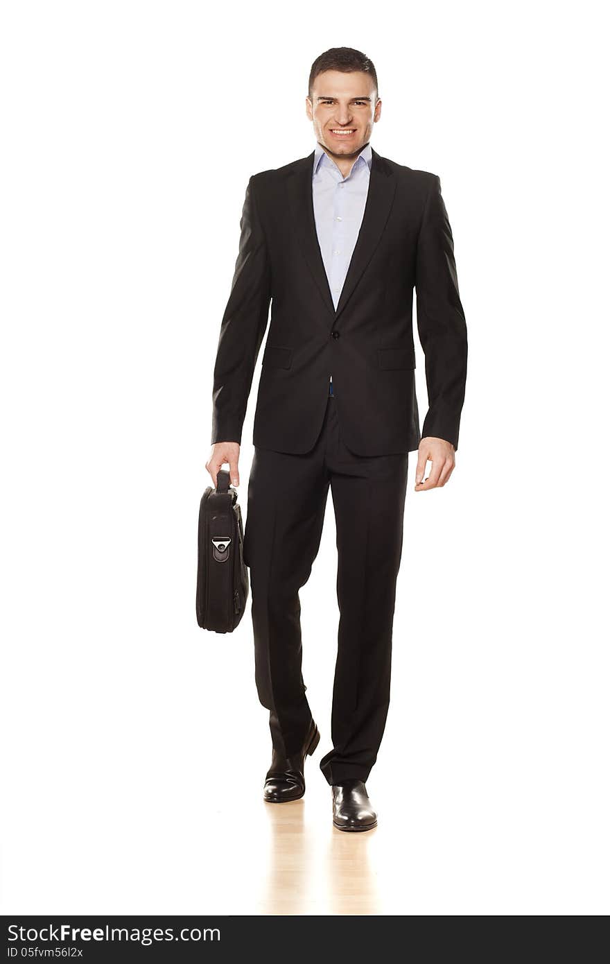 Studio shot of attractive smiling young businessman walking with a laptop bag. Studio shot of attractive smiling young businessman walking with a laptop bag