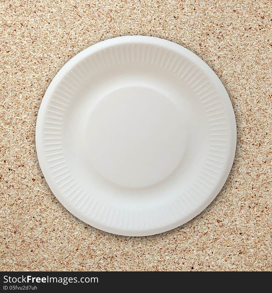 Empty white plate on cork board background