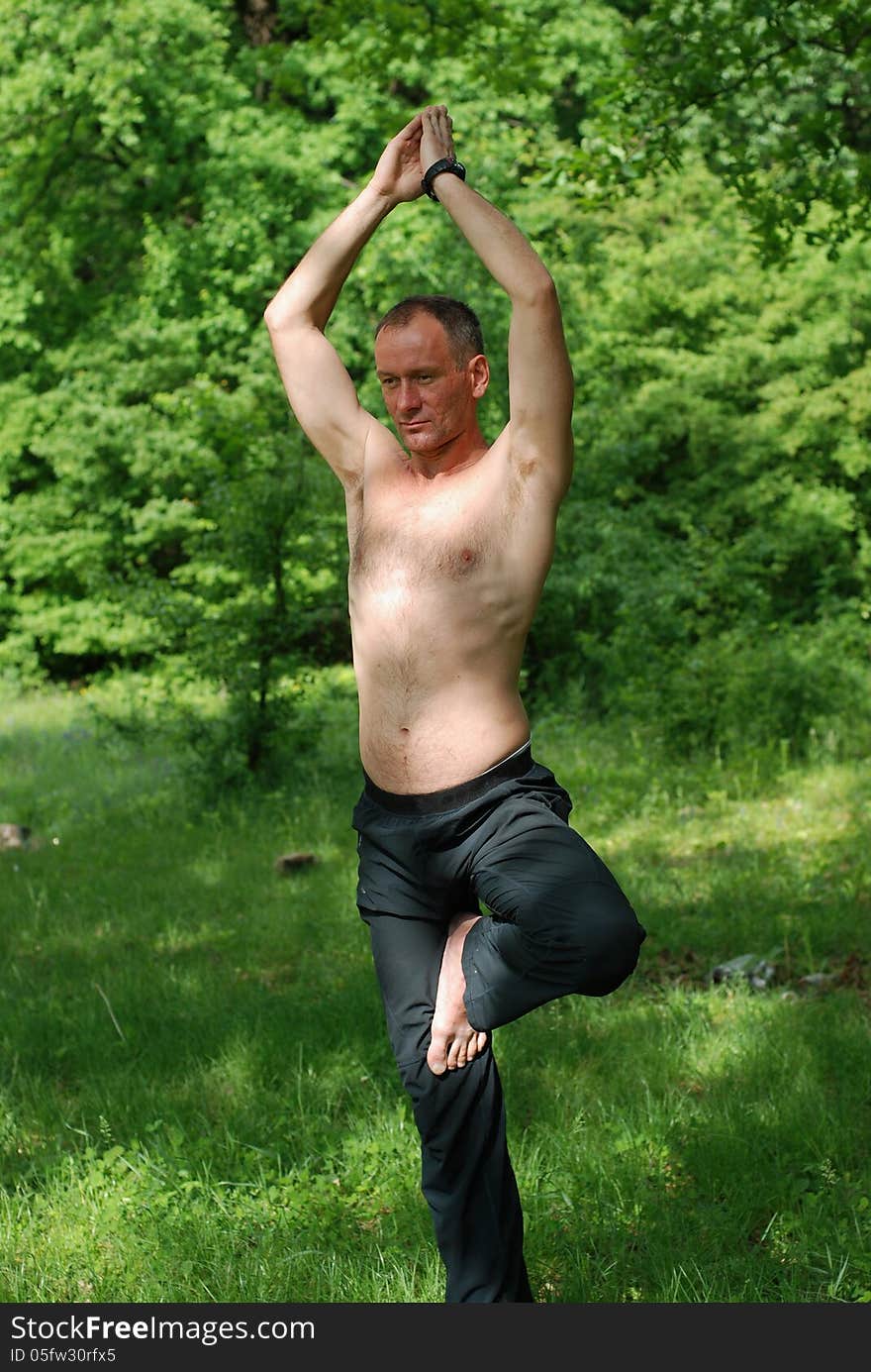 A man practices yoga in nature