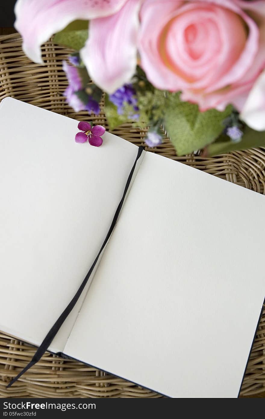 Blank page of notebook put on basket with flowers. Blank page of notebook put on basket with flowers