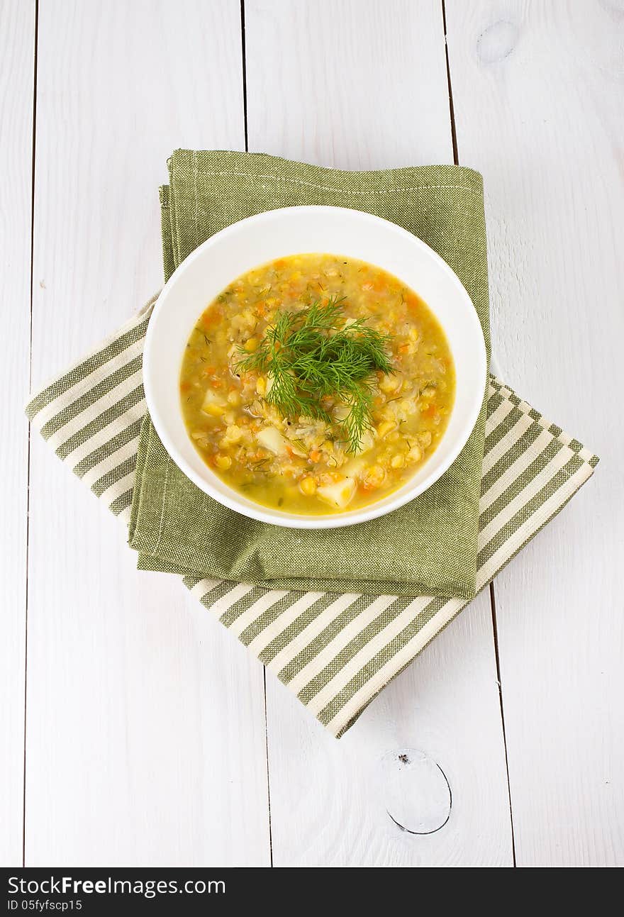 Yellow pea soup in bowl on white wooden background