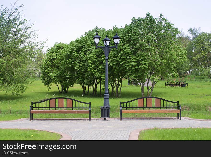 Classic style city lamp and wooden benches in green springtime park. Classic style city lamp and wooden benches in green springtime park