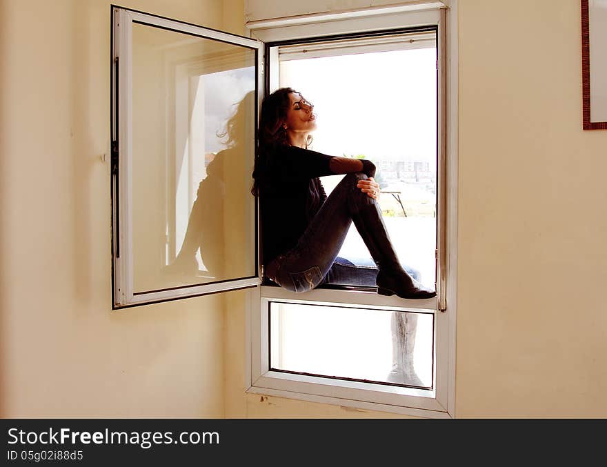 Portrait of beautiful woman sitting on the window