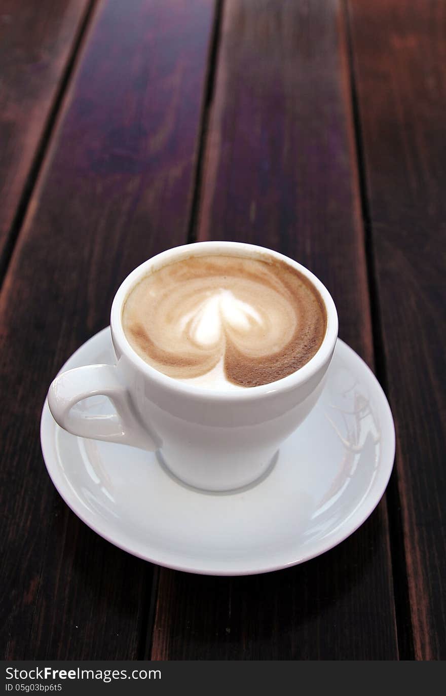 Cup of coffee on old wooden table on the beach