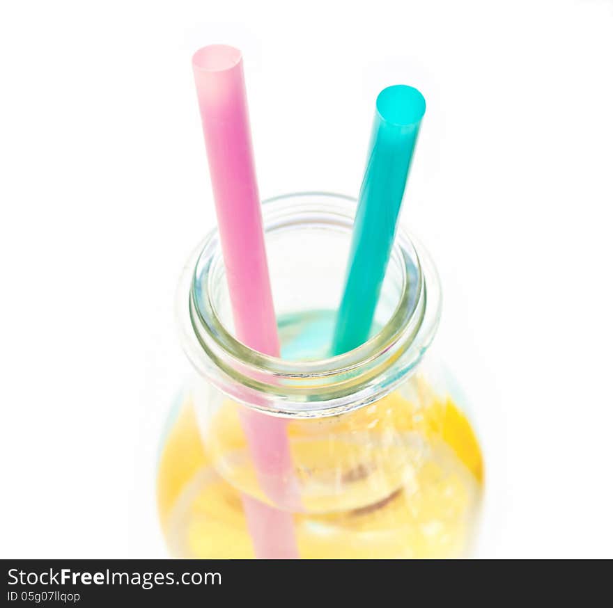 Cold lemon water in a glass with two straws, isolated on white background. Cold lemon water in a glass with two straws, isolated on white background