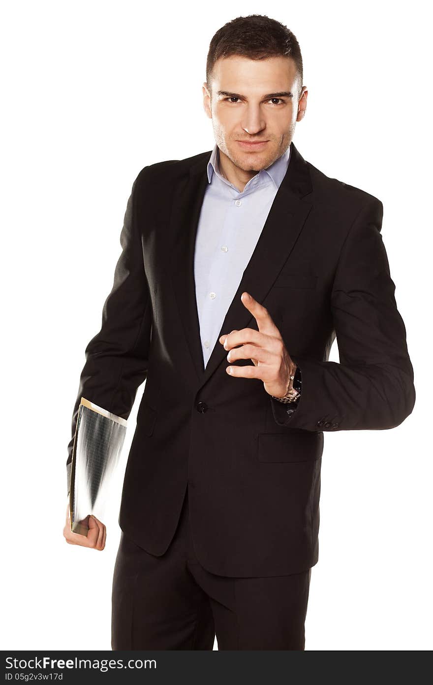 Smiling young businessman with folder in hand pointing a finger upwards