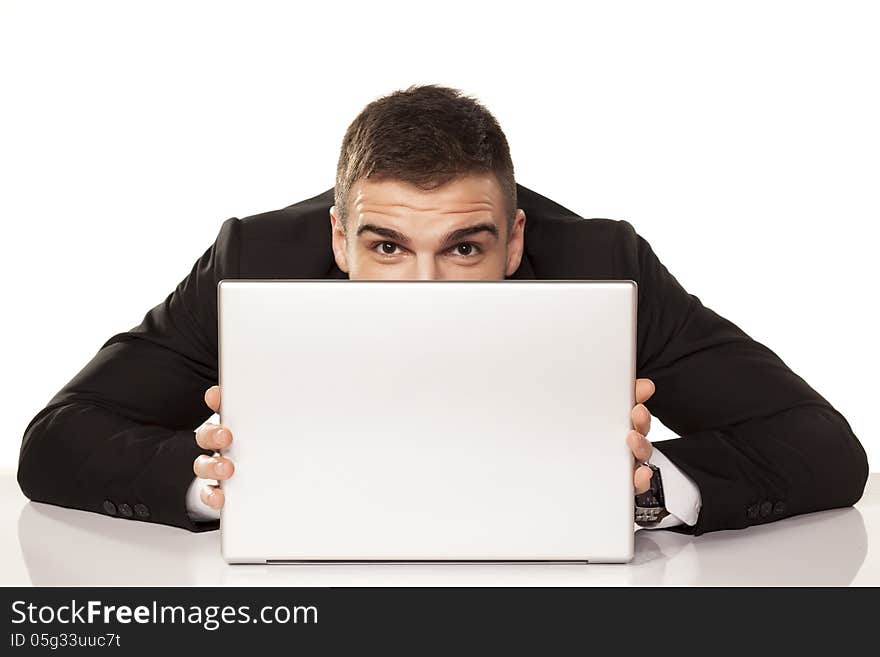 Young and funny businessman hiding behind his laptop. Young and funny businessman hiding behind his laptop