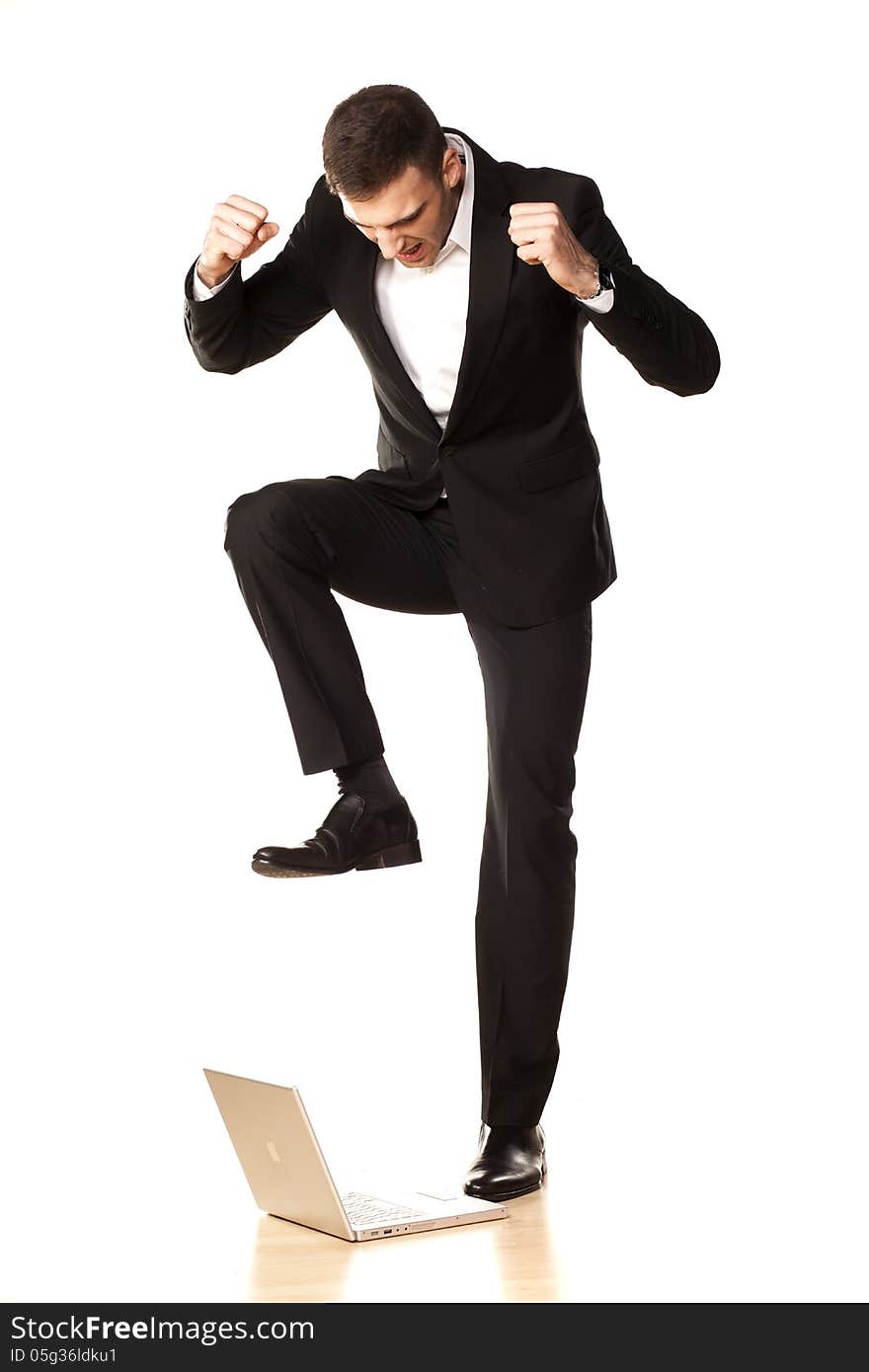 Young and attractive furious businessman in black suit, destroying his laptop using his foot. Young and attractive furious businessman in black suit, destroying his laptop using his foot