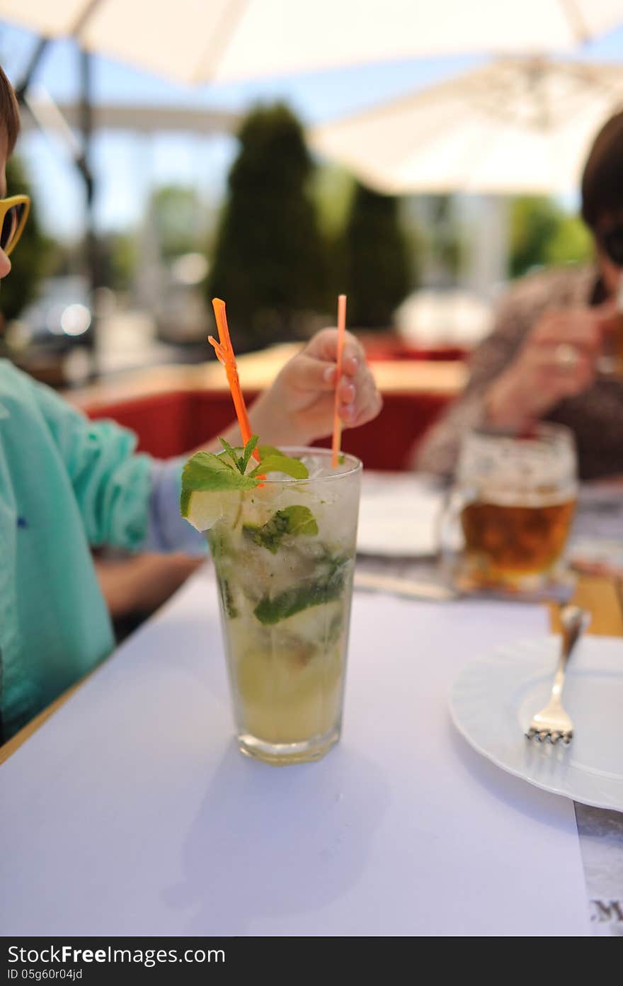 Close-up of a glass of cold drink mojitos with colored straws