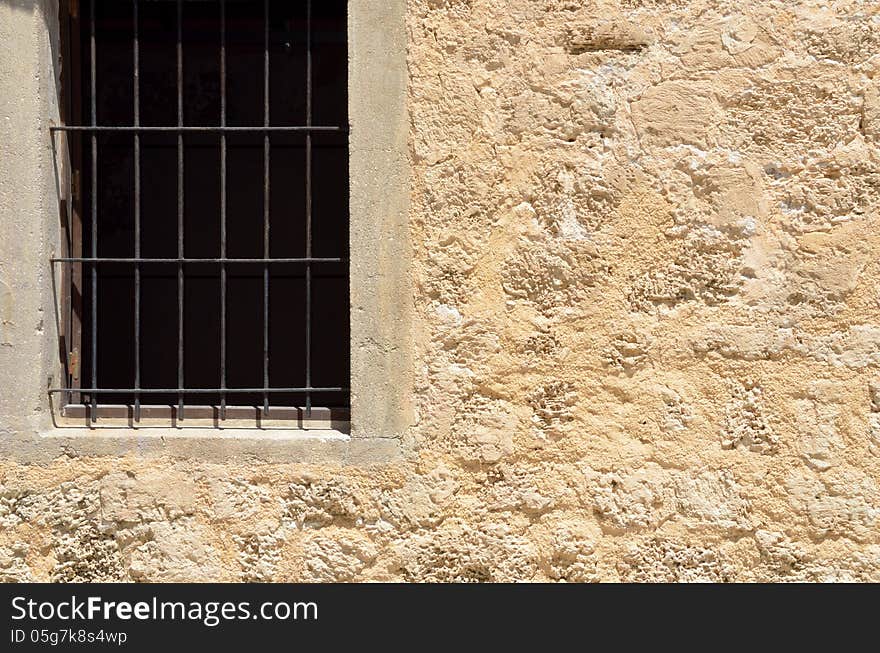 Fragment of old stone wall with window and grille. Fragment of old stone wall with window and grille