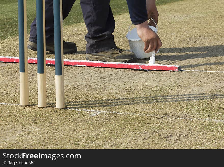 Touching up the batsman's crease during the lunchtime interval at cricket match. Touching up the batsman's crease during the lunchtime interval at cricket match