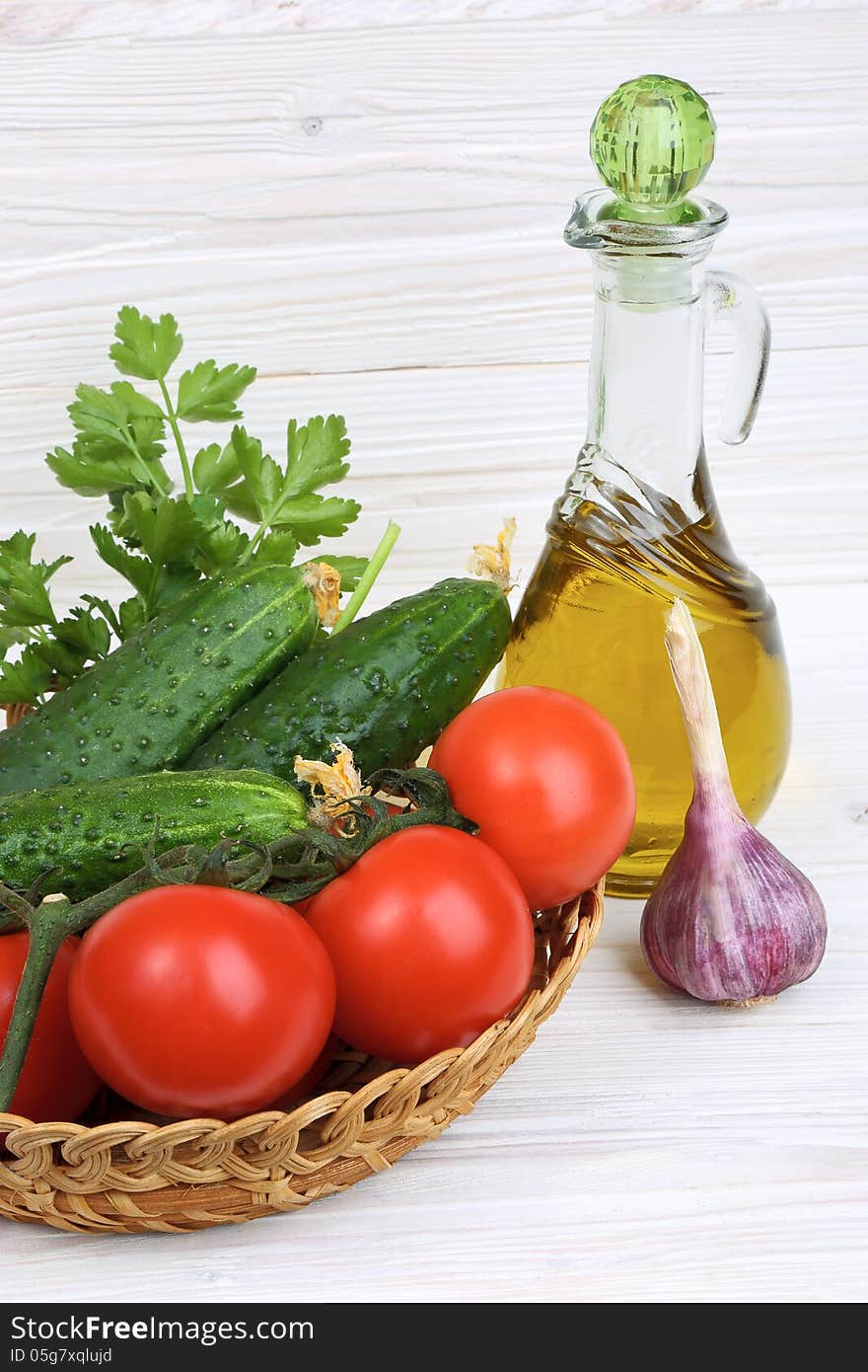 Vegetables and a bottle of olive oil on a light wooden background