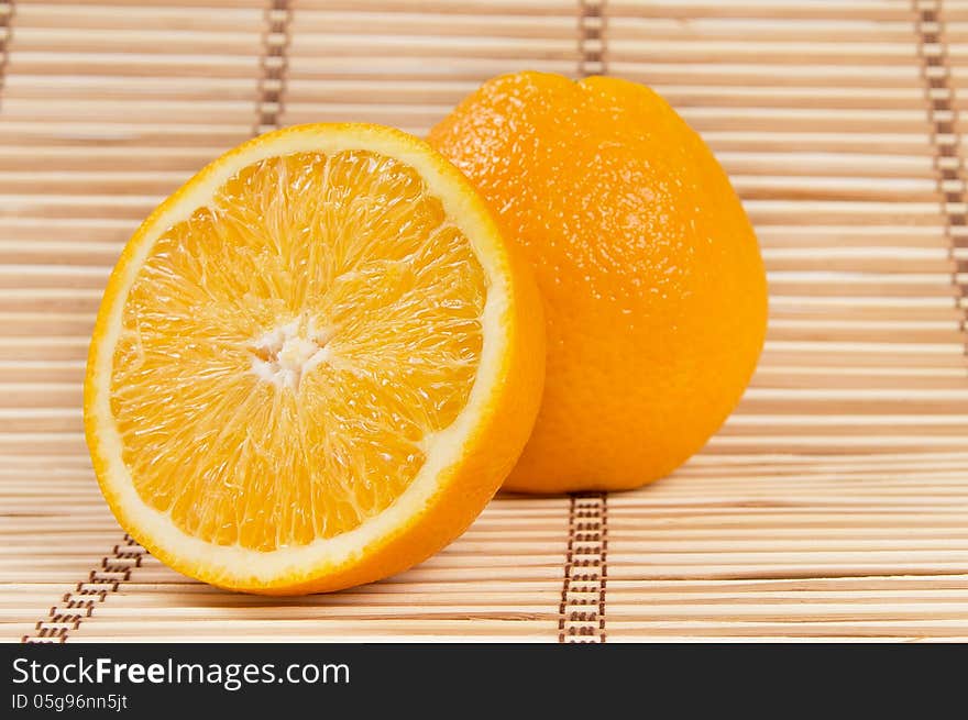 Whole orange fruit and his segments on bamboo background