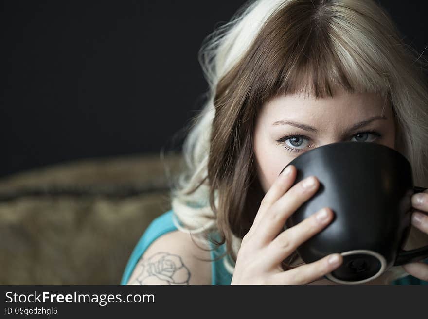 Portrait of a beautiful young woman with brown and blond hair looking right into the camera. She is also holding a black coffee cup and wearing a blue dress. Portrait of a beautiful young woman with brown and blond hair looking right into the camera. She is also holding a black coffee cup and wearing a blue dress.