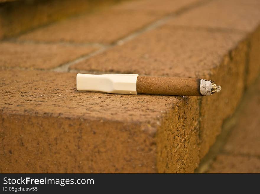 Closeup of a cigar left on a brick step.