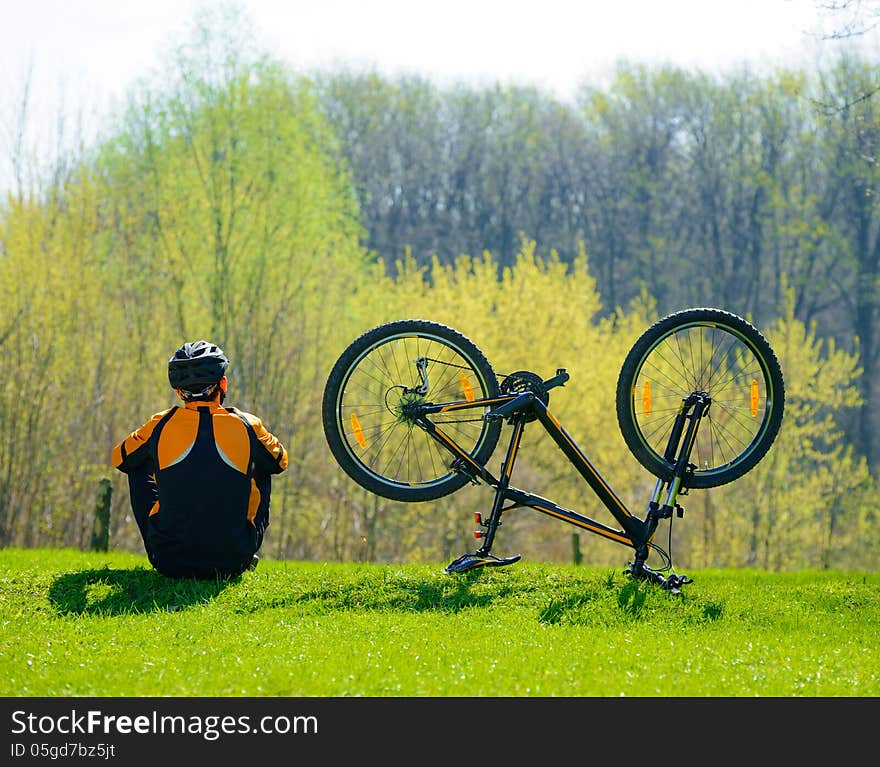 Cyclist Sitting on the Grass Near His Bike