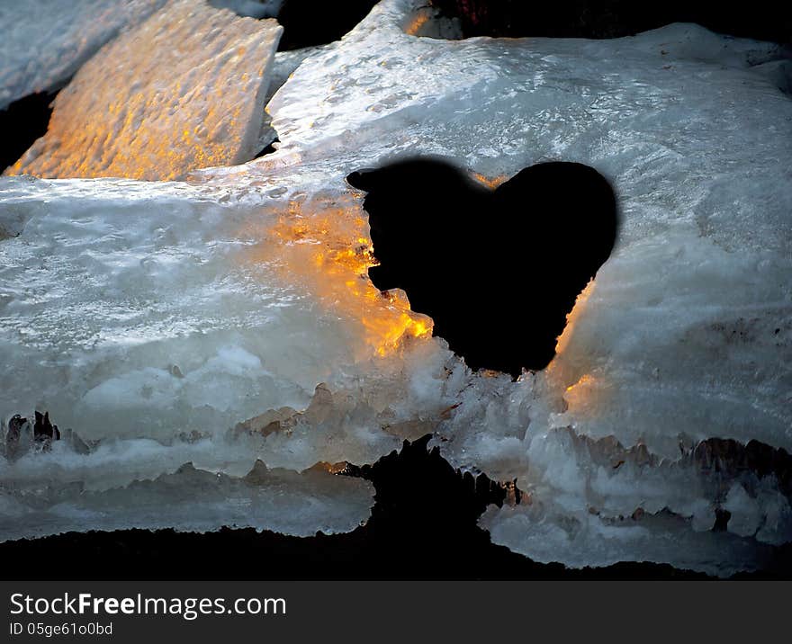 Ice with hole like a heart beautifully lit by golden evening sun. Ice with hole like a heart beautifully lit by golden evening sun