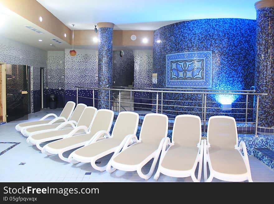 Chaise lounger in medical spa pool room near decorative blue wall. Chaise lounger in medical spa pool room near decorative blue wall.